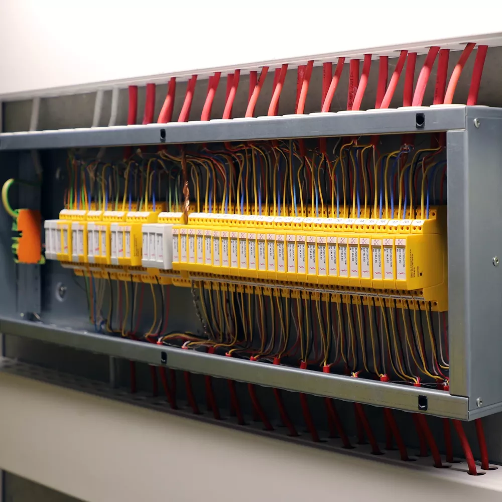 A close-up view of an open electrical control panel with multiple wires connected to yellow terminal blocks.